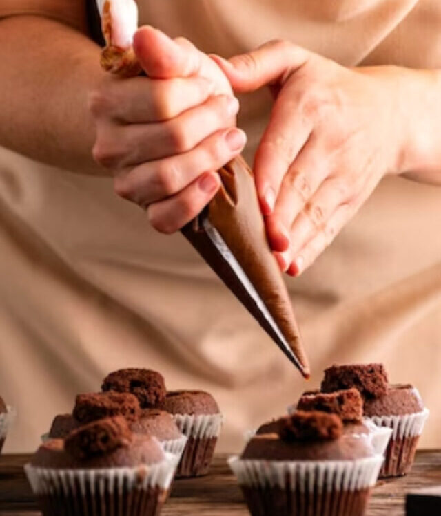 cropped-woman-decorates-muffins-with-chocolate-cream-kitchen-pastrycook-hand-prepare-chocolate-cupcakes_134398-16665.jpg